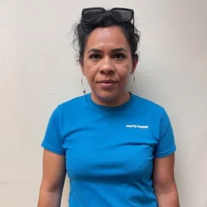 dolores is wearing a blue merry maids tshirt standing in front of a white wall